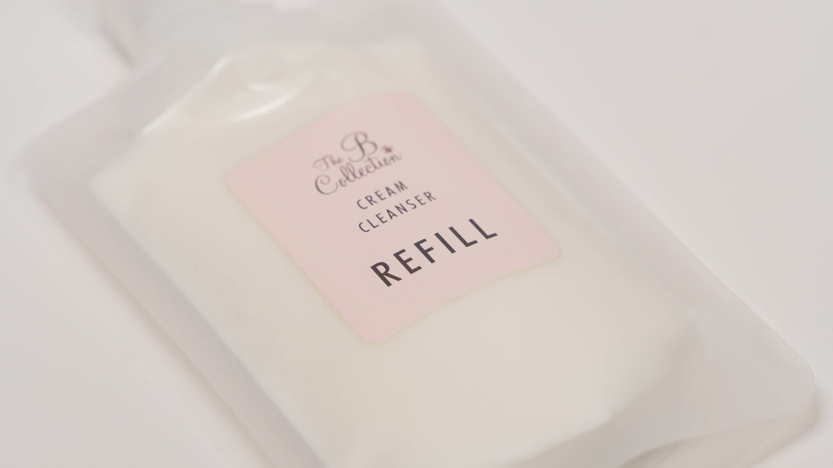 A refill pouch of The B Collection Cream Cleanser, showing the white cleanser inside a translucent white pouch with a light pink label, set against a plain white background.